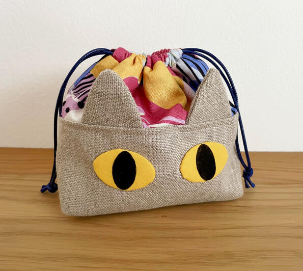 A drawstring bag with ears and hand-printed cat eyes A drawstring bag with ears and hand-printed cat eyes